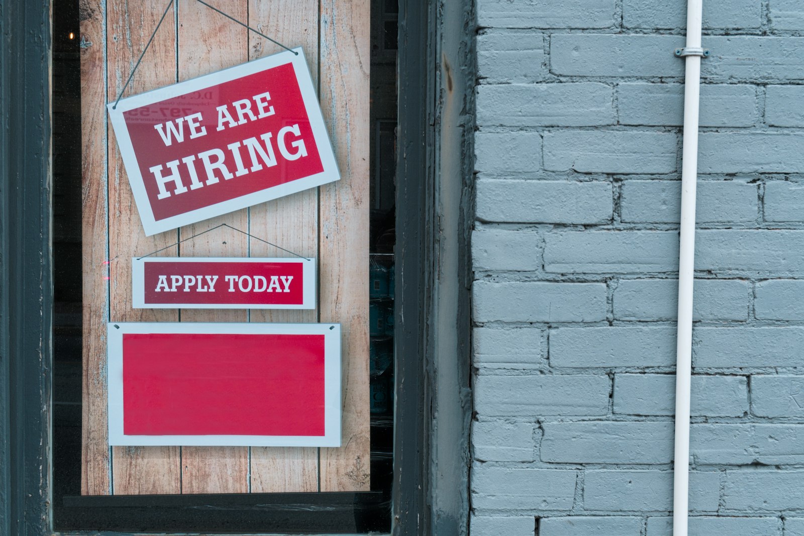 We are hiring — Apply today sign on a shop window